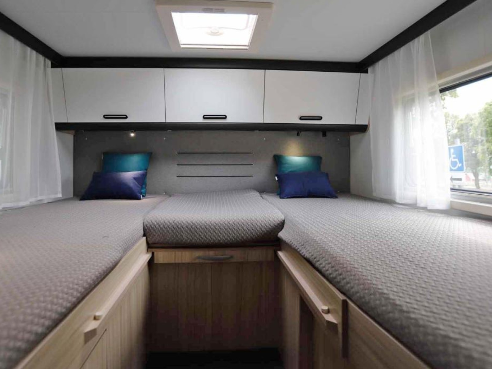 Zijaanzicht van de enkele lengtebedden achterin de Sun Living S72DL camper, met zicht op de doorgang naar de dinette en een overzicht van de ruime indeling